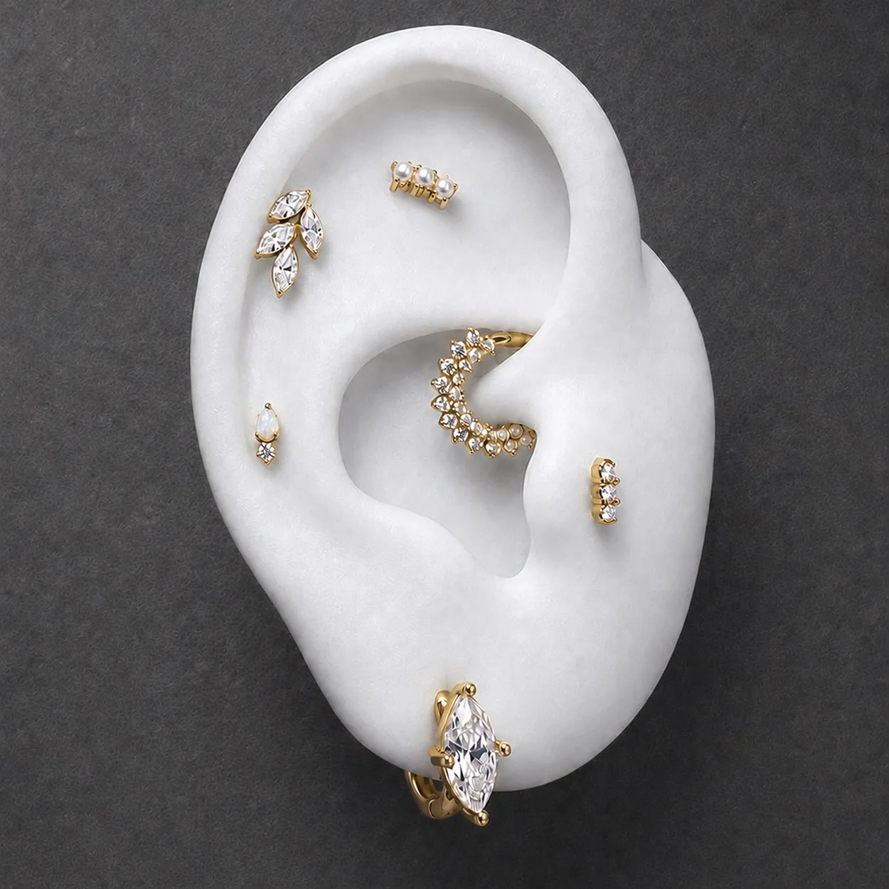 Pendientes de oro de Adamina sobre oreja de maniqui en fondo oscuro