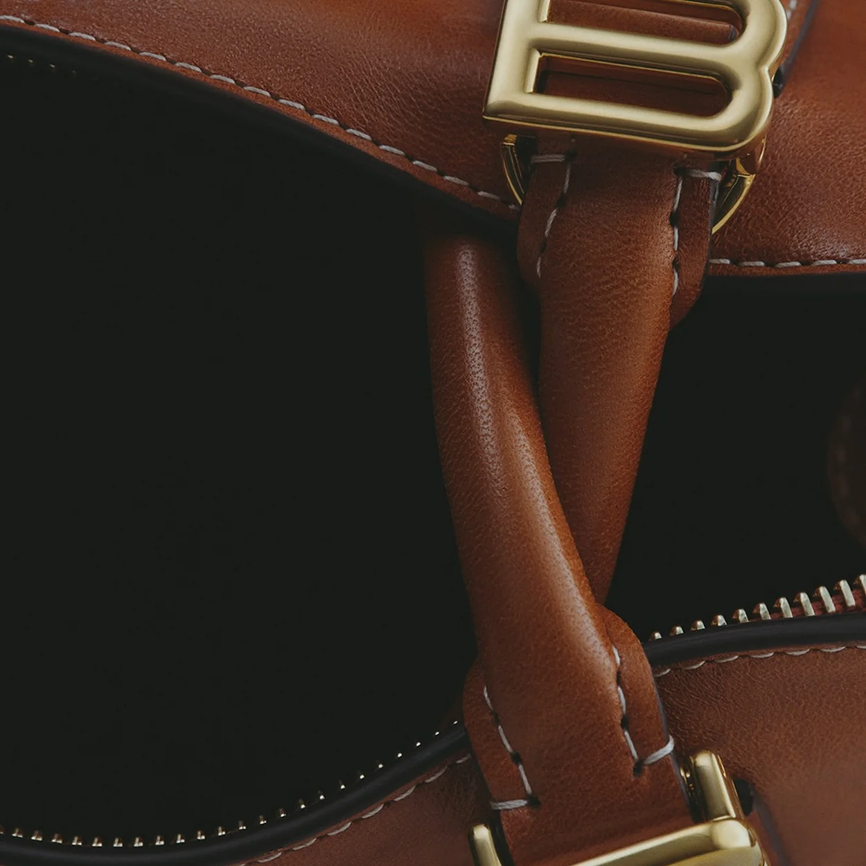 Detalle de la hebilla dorada de un bolso marron de Balenciaga