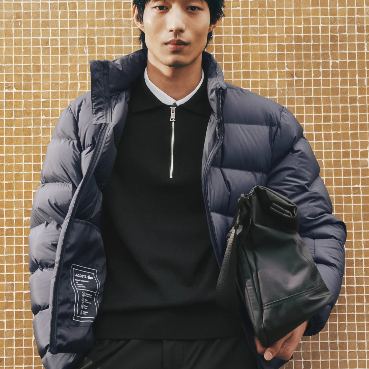 Hombre con plumifero azul y bolso de Lacoste