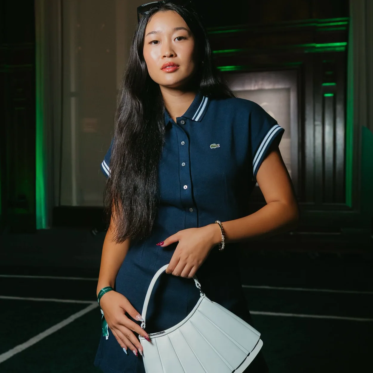 Modelo con vestido polo azul marino y bolso blanco de Lacoste