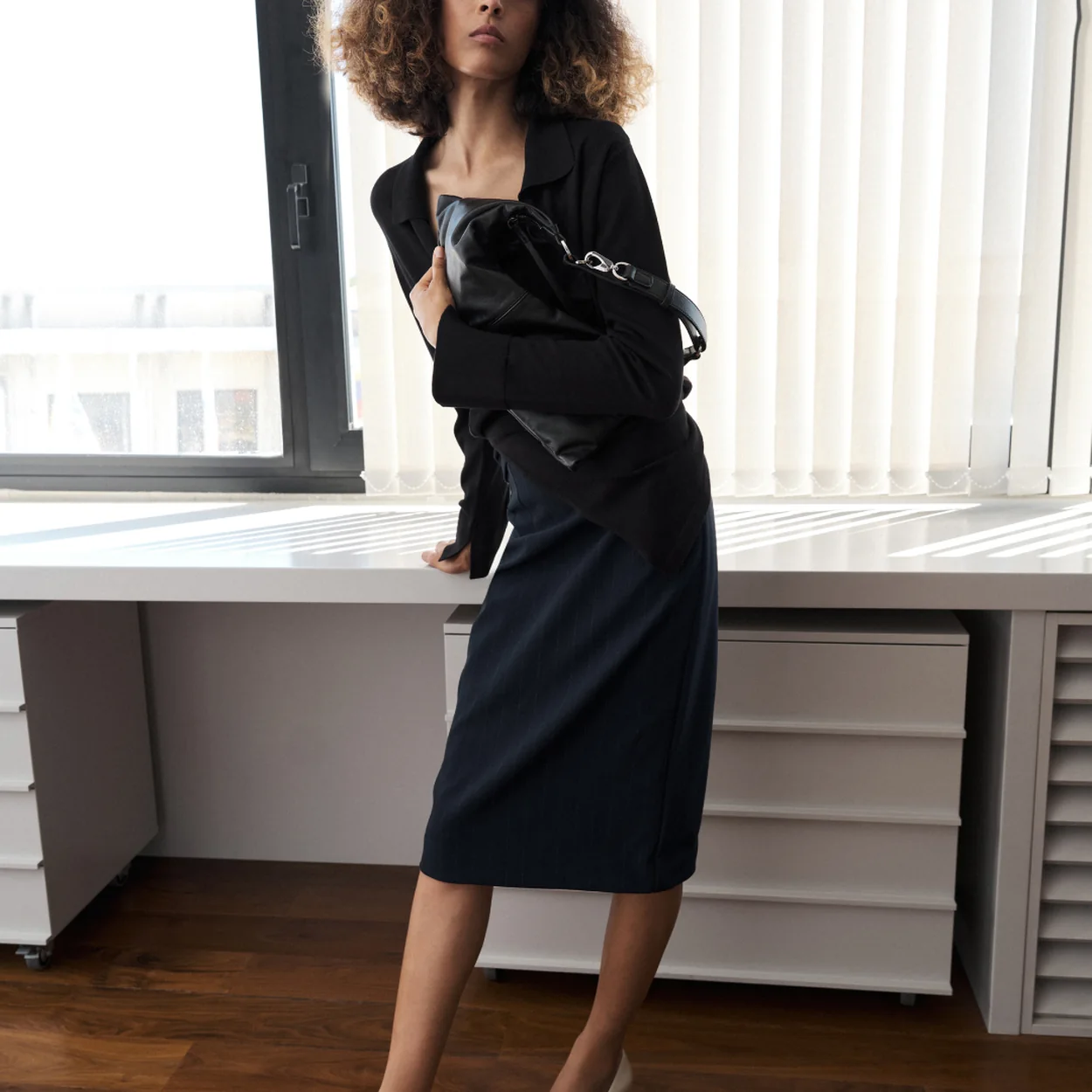 Modelo con falda midi negra y bailarinas de Mango