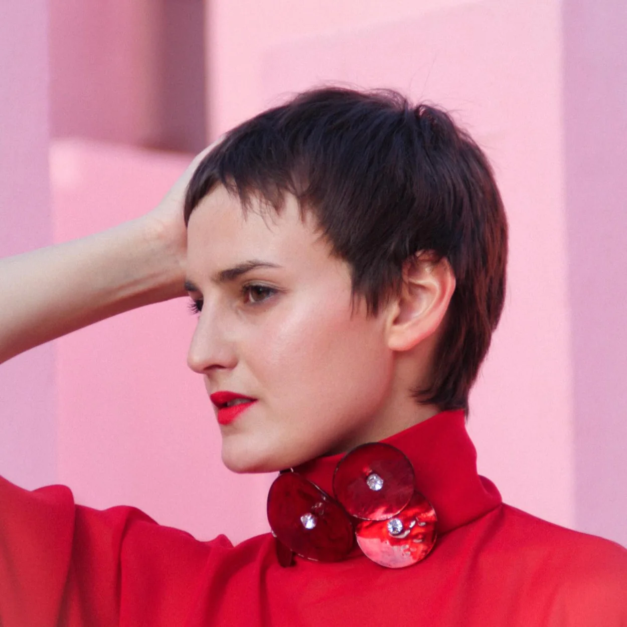 Blusa roja de cuello alto con broche de Marcos Luengo
