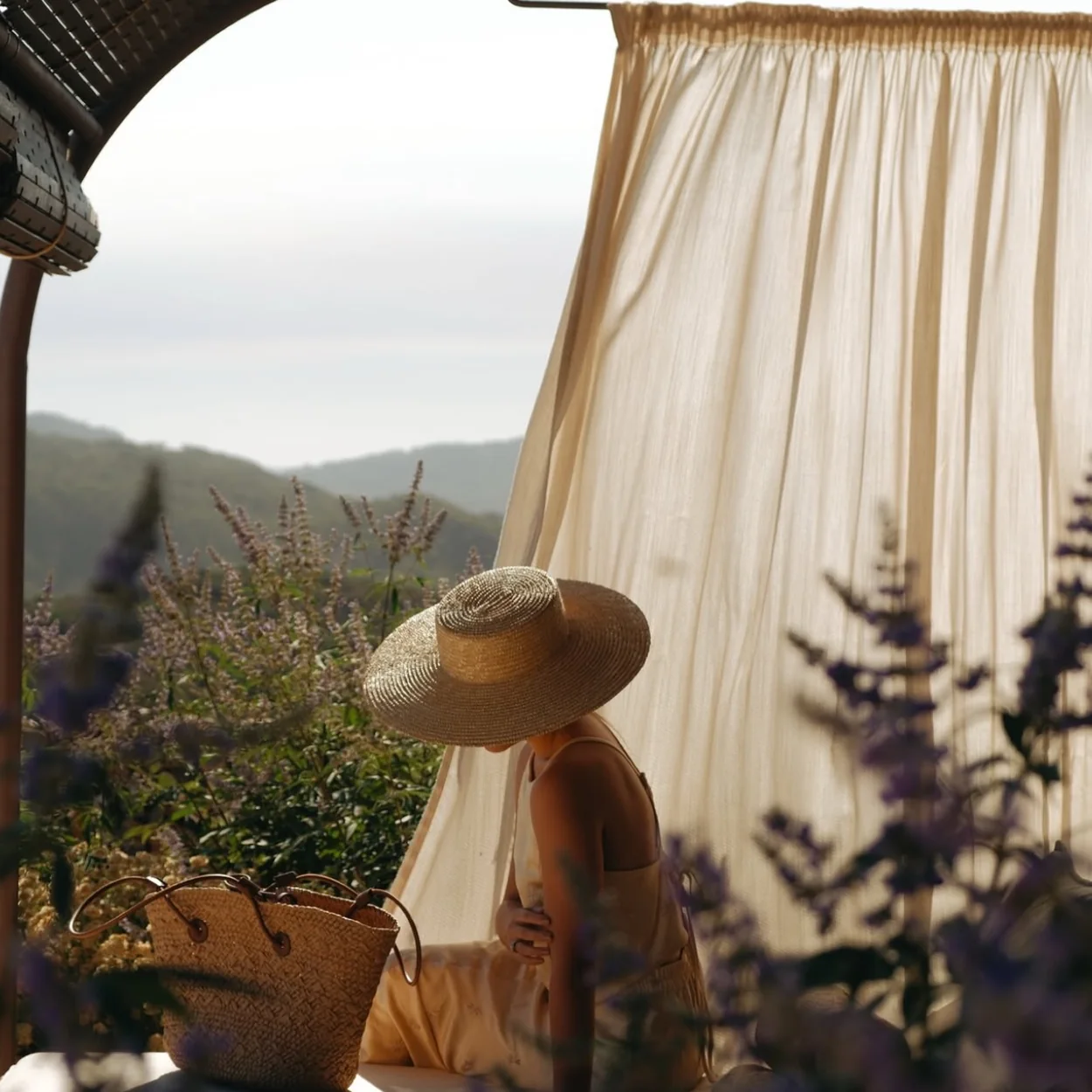 Pamela y bolso de rafia de Mimoki junto a una ventana