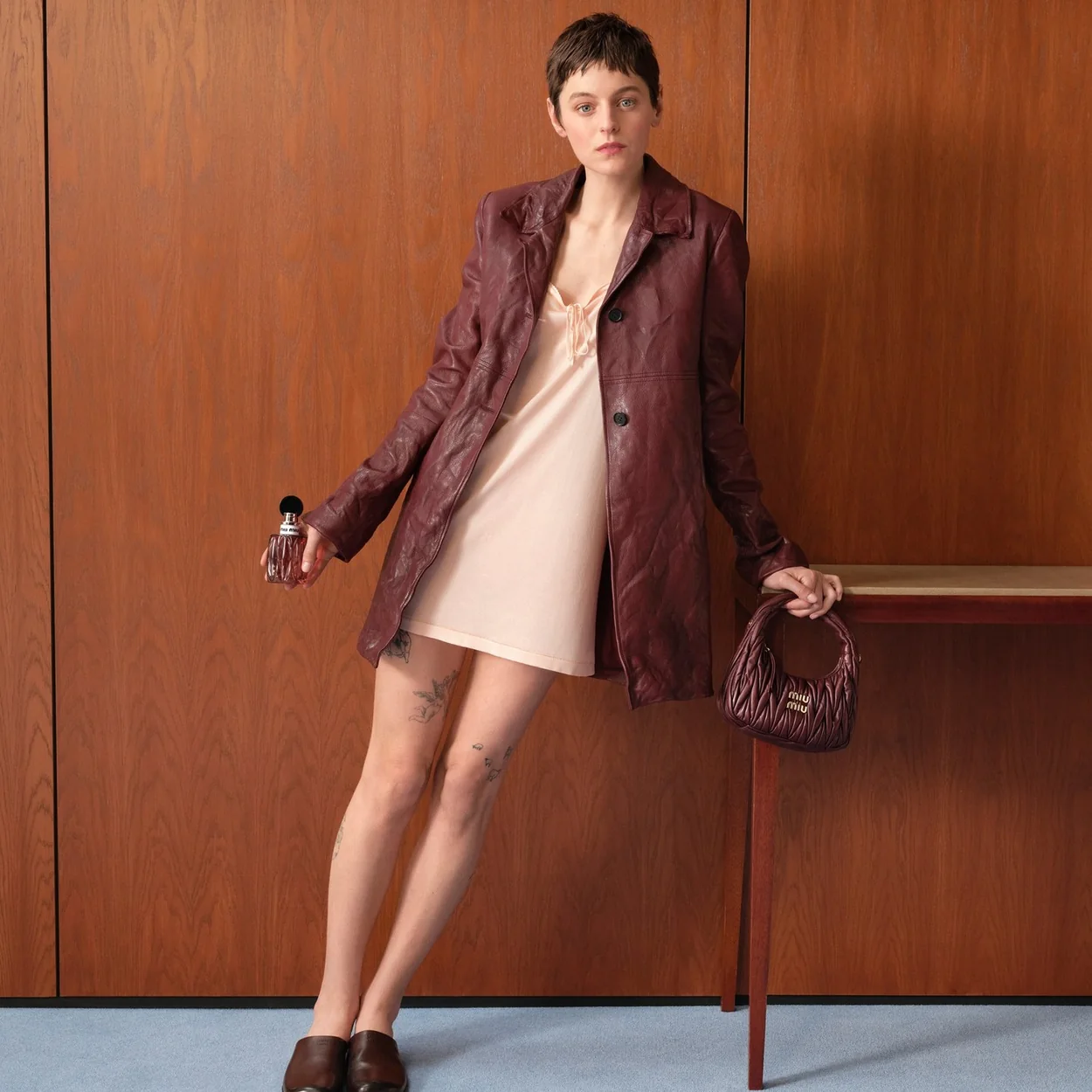 Modelo con cazadora de piel granate y vestido lencero de Miu Miu