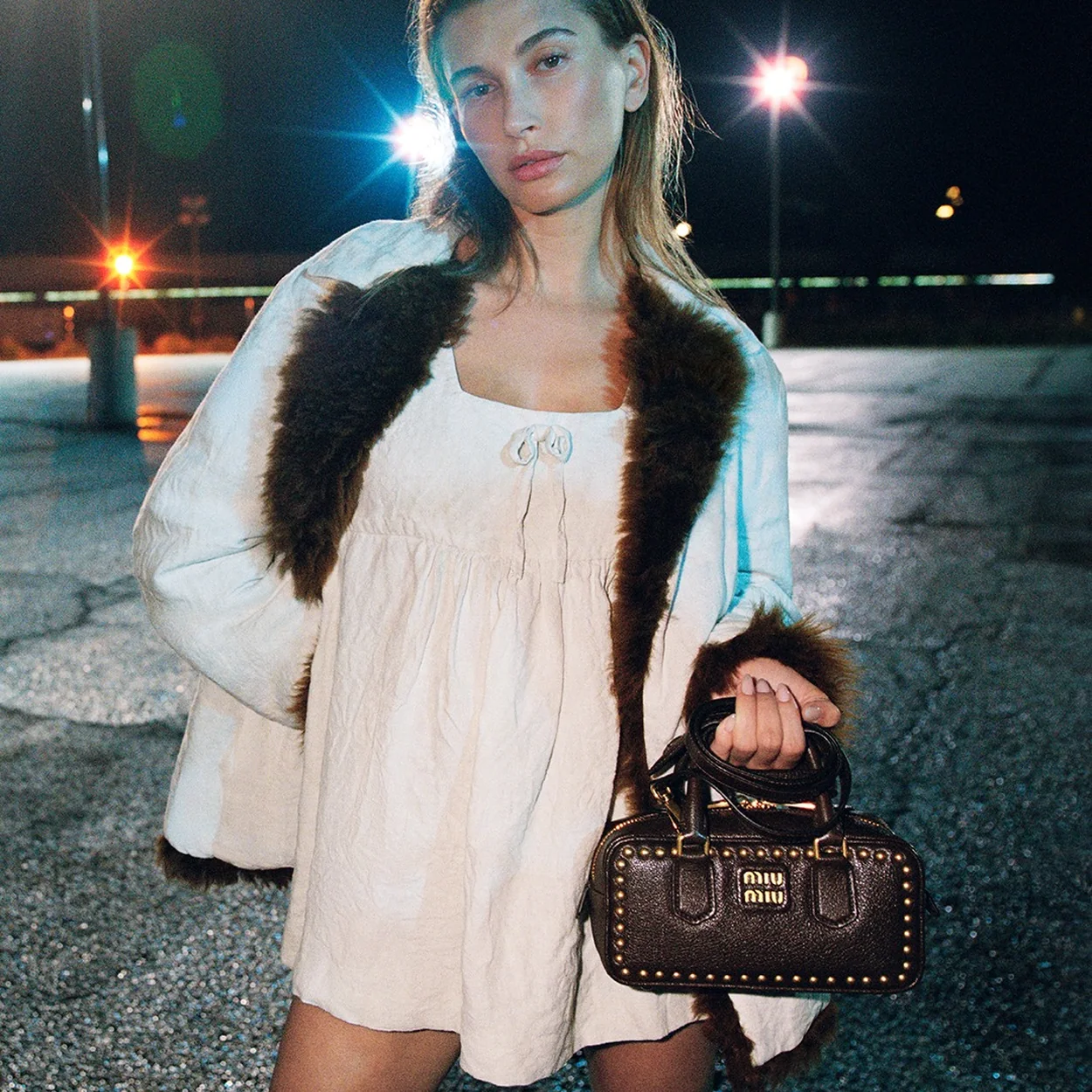 Modelo con vestido blanco y bolso con tachuelas de Miu Miu