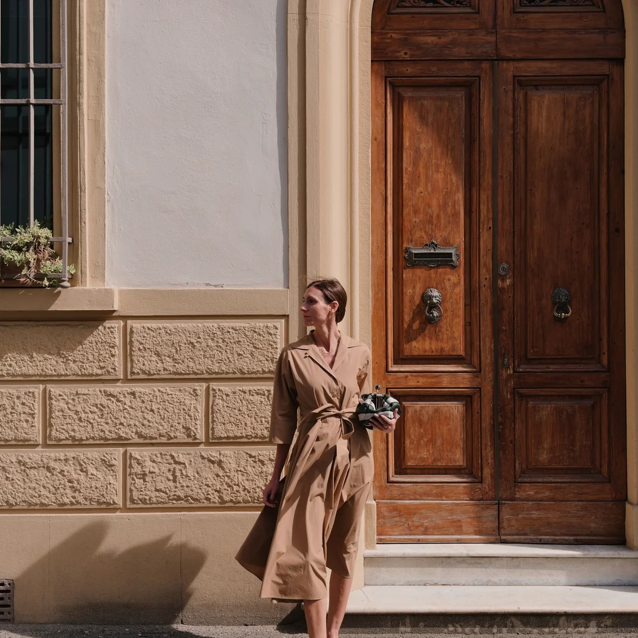 Modelo con gabardina y bolso de Weekend Max Mara ante un portal