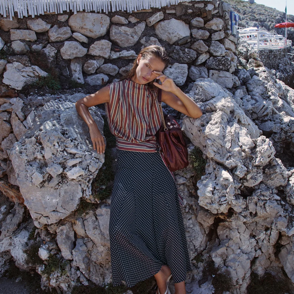 Modelo con top de rayas y falda gris de Zara junto al mar